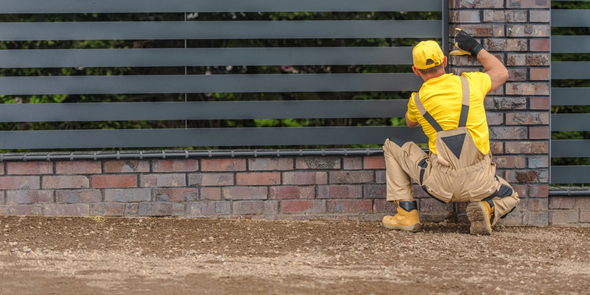 A man in yellow fixing a fence